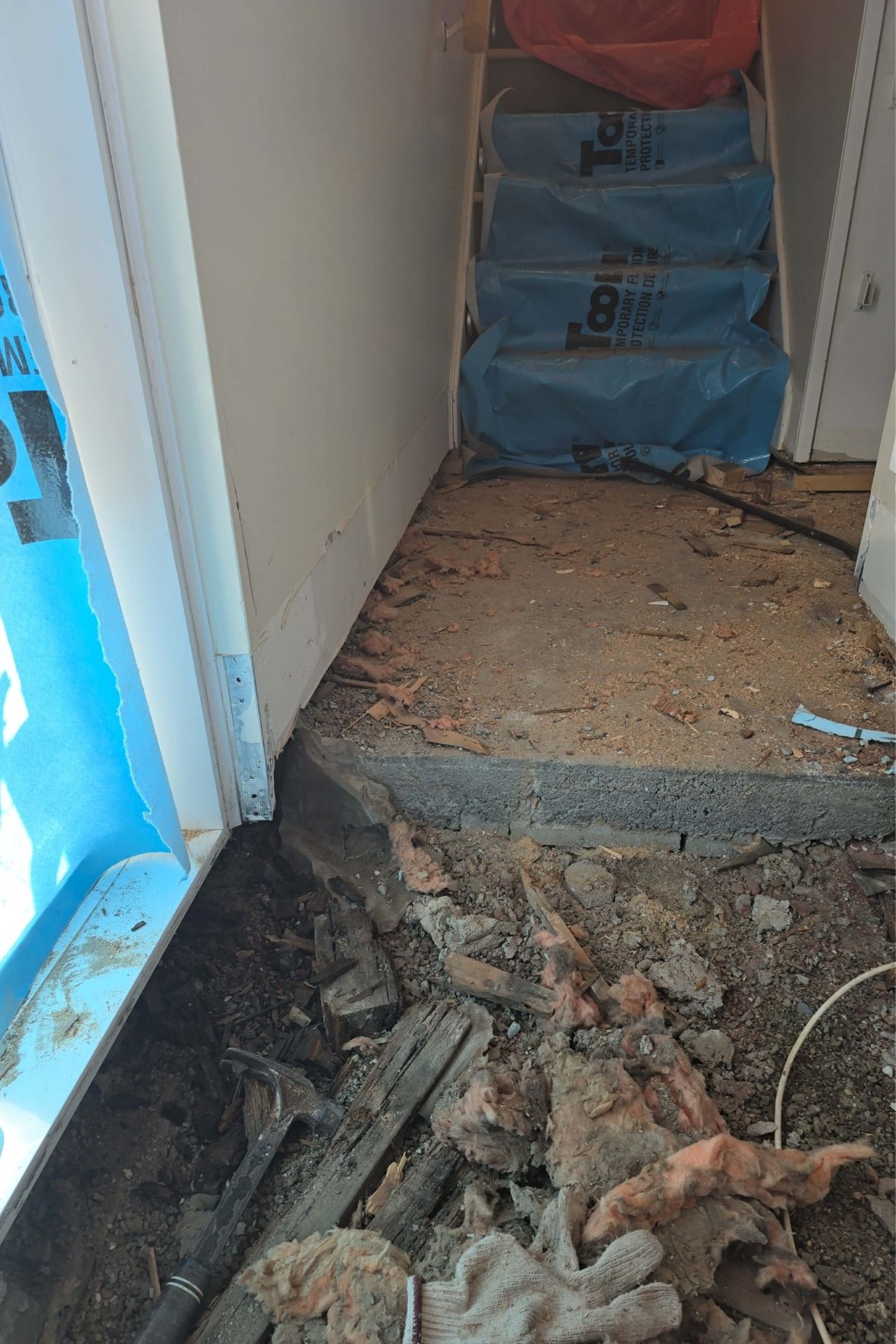 Escalier protégé par bâches plastiques et débris au sol dans un chantier intérieur  à Laval