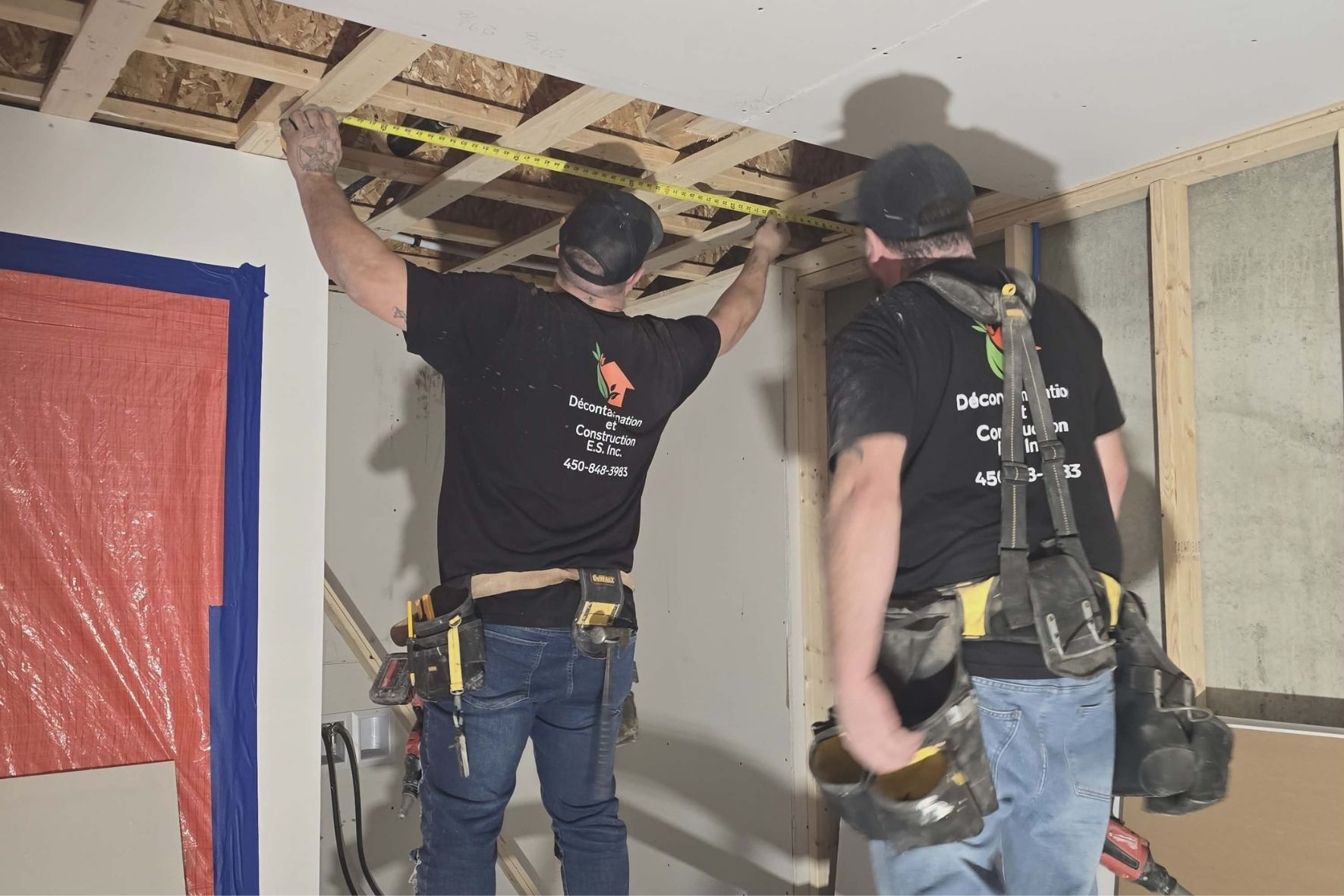 Deux travailleurs mesurant une structure intérieure en bois dans un espace rénové  à Saint-Jérôme